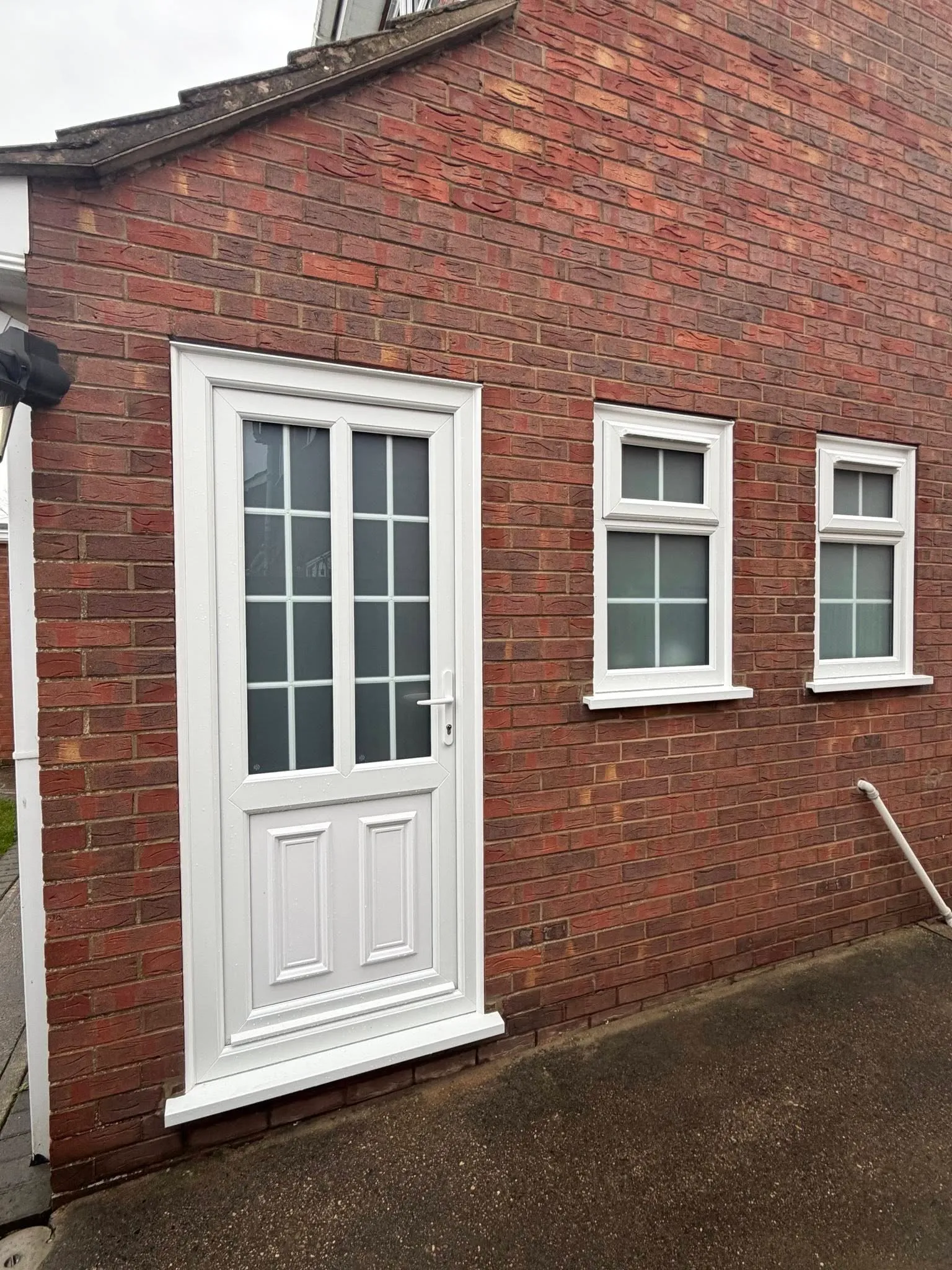 White uPVC front door and casement windows on a brick property